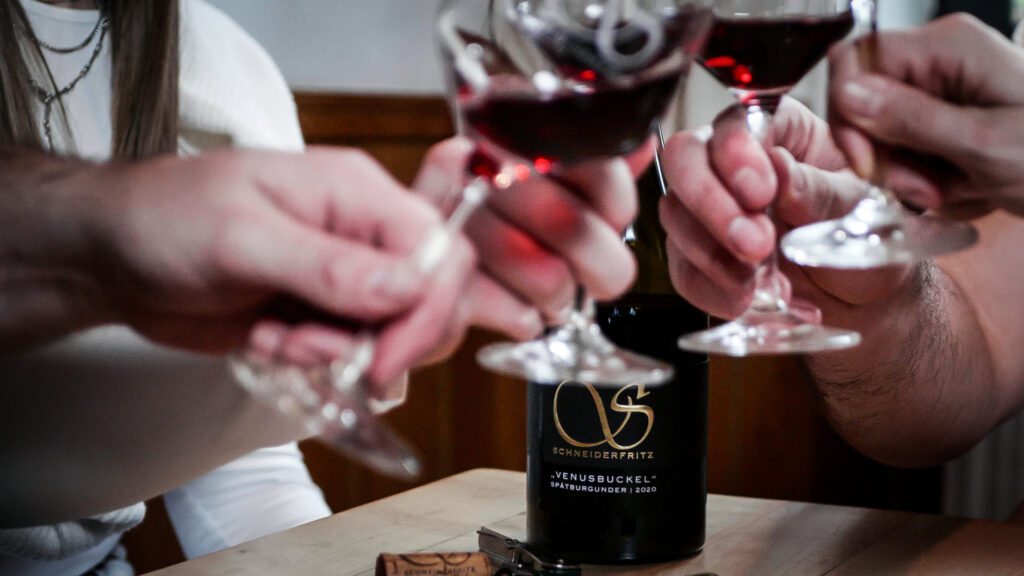 Leute in der Weinstube stoßen mit Wein an